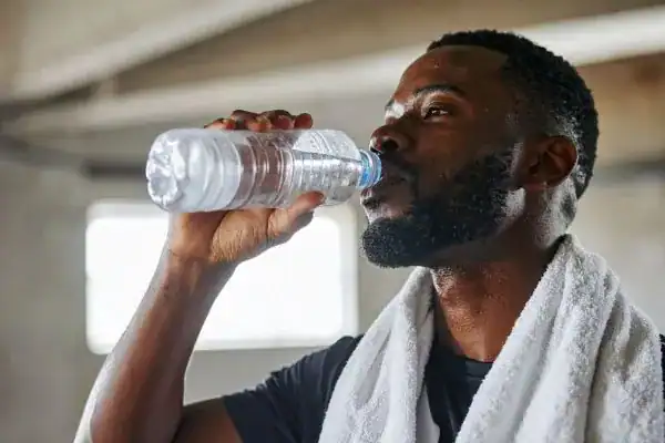 Image of man drinking water to improve hydration Scottish after work out.
